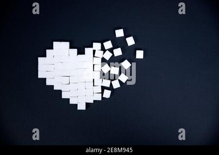 Heart made of cubes of sugar on a blue background. Diabetes, unhealthy lifestyle concept Stock Photo