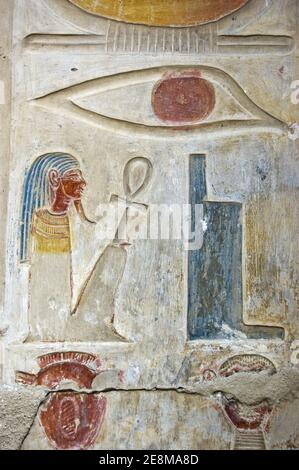 Ancient Egyptian hieroglyphs carved on a wall of Abydos Temple near el Balyana, Egypt. An eye, throne, squatting pharaoh and two heads.  Ancient carvi Stock Photo