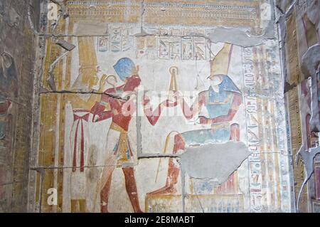 Ancient Egyptian bas relief showing Pharaoh Seti I taking a royal flail from Horus with goddess Maat standing behind.  Abydos Temple, el Balyana, Egyp Stock Photo