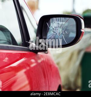 Red car with broken side door mirror parked on the street Stock Photo