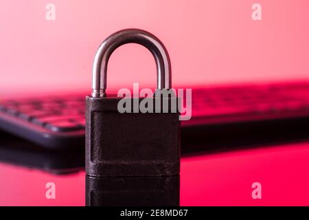 Locking the computer keyboard. The lock and keypad are tinted red. Information security concept. Stock Photo