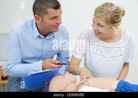 male instructor explaining cpr to his student using dummy Stock Photo