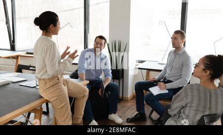 Diverse business team sitting in circle in office and talking Stock Photo