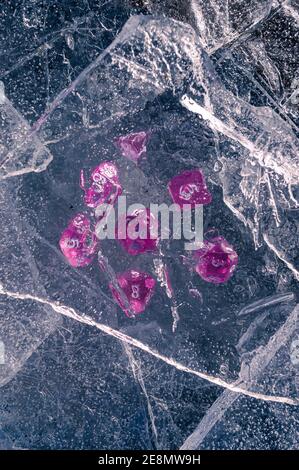 Image of a set of rpg dice beneath a sheet of ice in the winter's sun Stock Photo
