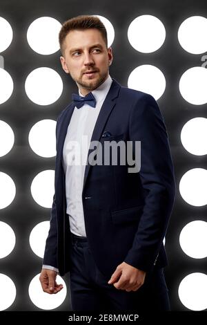 elegant handsome man in tuxedo posing against the backdrop of spotlights. night life Stock Photo