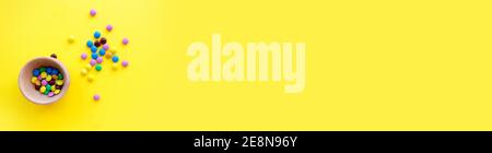 Sweet banner. Small colored candies, on a yellow background Stock Photo
