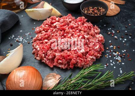 Minced turkey meat with onion and rosemary on a black background. Stock Photo