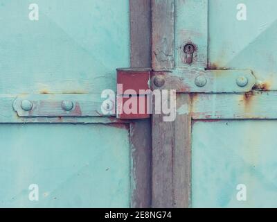 Massive steel door latch with armored padlock. Metal obsolet door  in light green pain Stock Photo