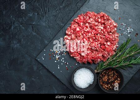 Ground beef with salt and pepper on a black background. Top view with copy space. Stock Photo