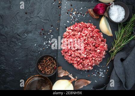 Fresh minced meat with onion and rosemary on a black background. Stock Photo