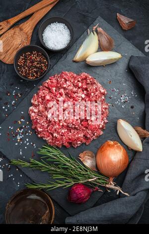 Fresh minced minced pork on a black background. Culinary background, vertical orientation. Stock Photo