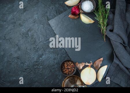Cooking background with copy space, flat plate, onion and spices on black background. Stock Photo