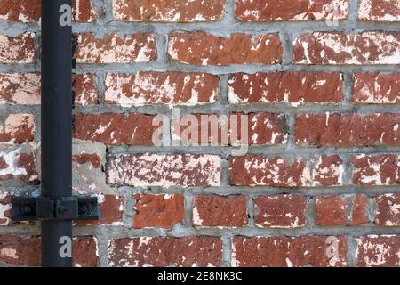 A red brick wall with a black steel pipe at left, a useful image for copy space. Stock Photo