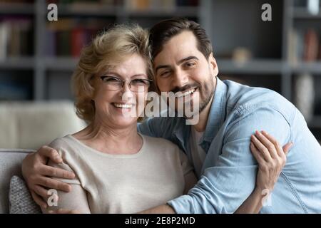 Portrait of smiling young man embracing senior mother in glasses. Stock Photo
