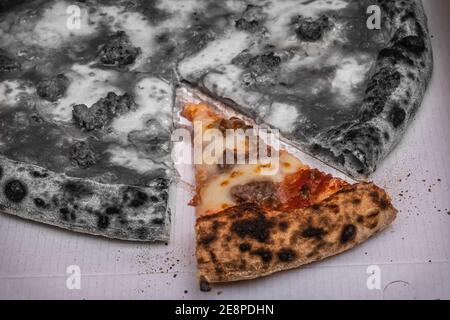 black and white image of pizza with one slice highlighted in color Stock Photo