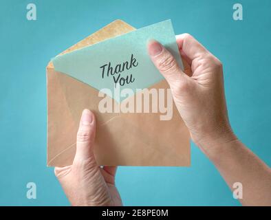 Woman open and look at thank you card or note inside a brown envelope. Close up view. Stock Photo