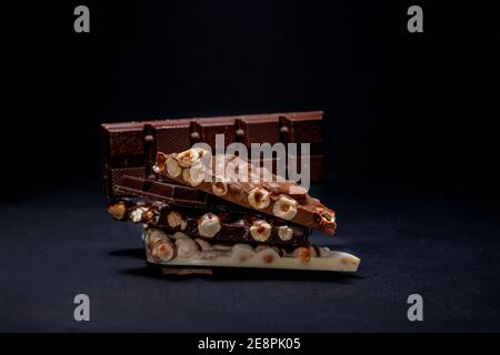 Dark and white chocolate with hazelnuts on a black background Stock Photo