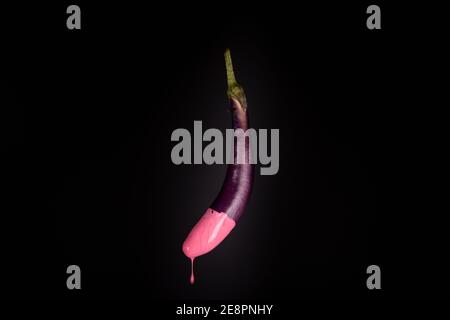 Eggplant isolated floating with pink dripping paint. Black background. Creative food concept Stock Photo