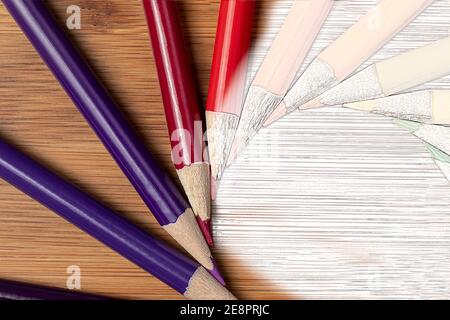 A Macro Shot of Sharpened Colored Pencils in a mixed media photo and sketch shot in a vortex spiral offset pattern on a bamboo table.  Colors follow t Stock Photo