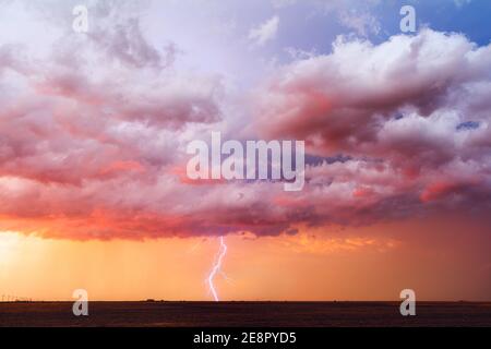 Stormy sunset sky with dramatic clouds and lightning strike as a thunderstorm approaches Perryton, Texas Stock Photo