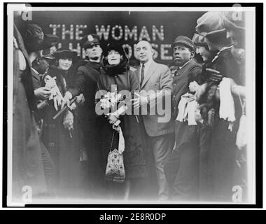 Mildred Harris Chaplin, full-length portrait, standing in crowd, facing front, guarded by a policeman Stock Photo