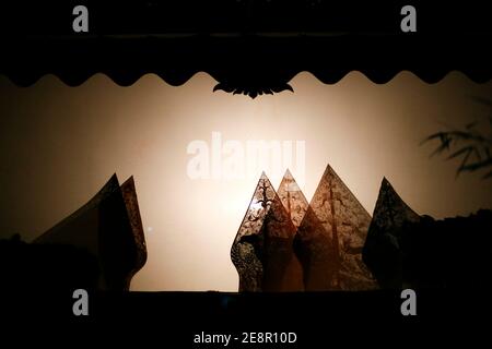 Indonesian puppet called wayang kulit performing on screen at night Stock Photo