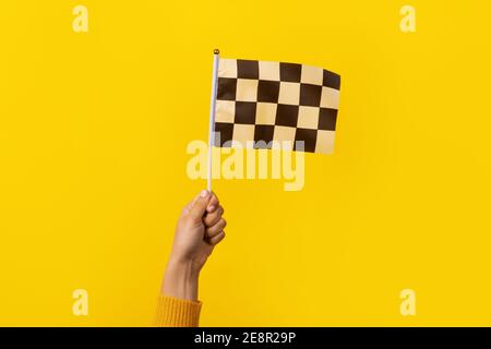checkered flag in hand over yellow background Stock Photo