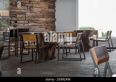 table with a wooden log and a glass, elegant furniture in a cafeteria illuminated with natural light, interior design Stock Photo