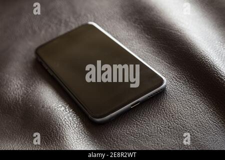 modern cell phone with metallic border on a very elegant leather armchair with soft light and contrast Stock Photo