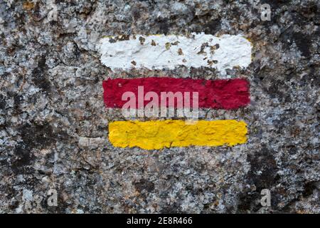 Trail marking sign with white, red and yellow stripes painted on wall Stock Photo
