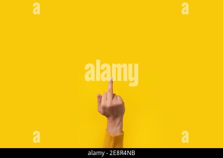 Hand gesture, fuck you symbol, middle finger sign over yellow