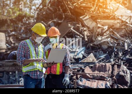 Professional Industrial Mechanical Engineer with Factory Worker while Using Laptop Computer at Metal lathe industrial manufacturing factory. Engineer Stock Photo