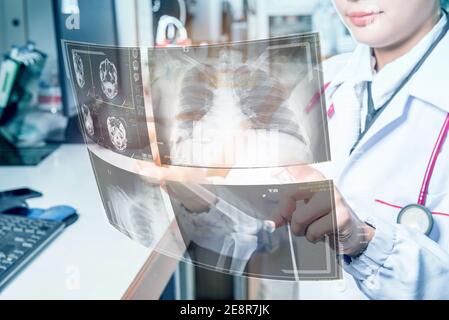 Doctor in futuristic medical concept pressing button operating futuristic medical interface with X-rays and digital screens. Stock Photo