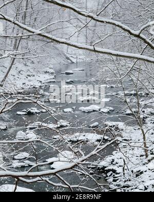 View of Rock Creek in Washington, DC, with snow-covered boulders and trees. Stock Photo