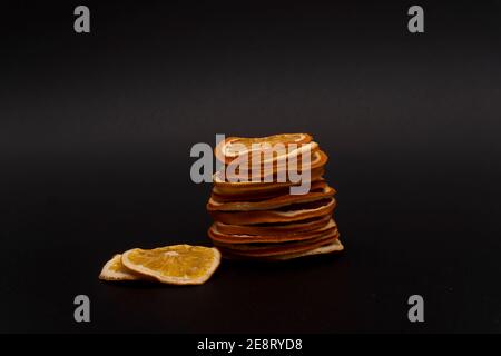 Stack of sliced dried dehydrated oranges and two sliced of dried oranges nearby Stock Photo