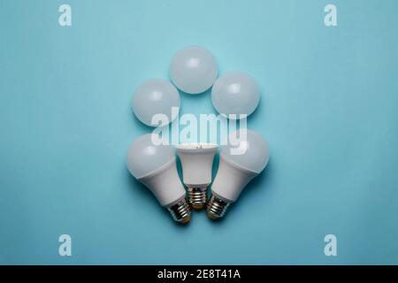 Creative geometric composition with LED lights on a blue background. One bulb without a diffuser in the armory of new whole bulbs and three white ligh Stock Photo