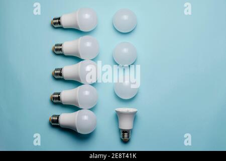 Creative geometric composition with LED lights on a blue background. One bulb without a diffuser, five new whole bulbs, and three white matte light di Stock Photo
