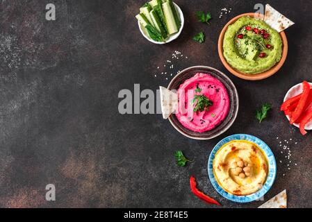 Colorful hummus bowls, healthy vegan dips. Traditional Middle eastern hummus, green hummus, beetroot hummus, spread. Assorted meze and dips with pita Stock Photo