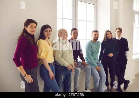 Group of people of different ages and nationalities is standing by a large window. Stock Photo