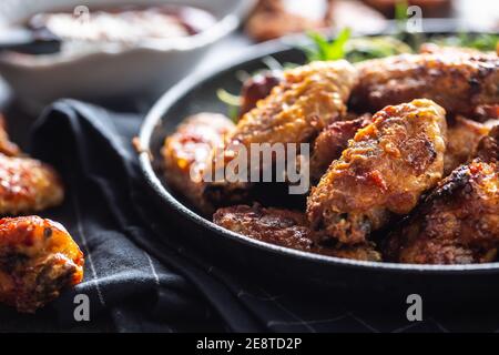 Chicken wings barbeque in a cast iron baking dish with BBQ sauce and rosemary Stock Photo