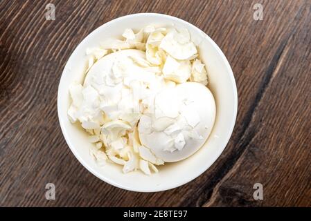 Two whole white chicken eggs are covered with shells. Bowl with eggs and shells. Close up. Stock Photo