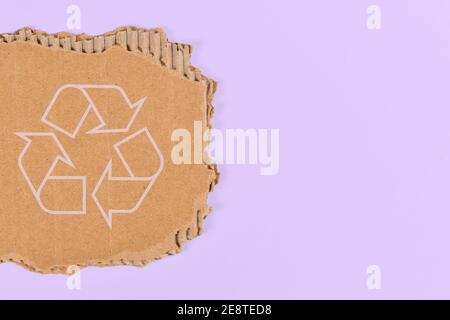 Piece of cardboard with recycling arrow sign on violet blue background with copy space Stock Photo