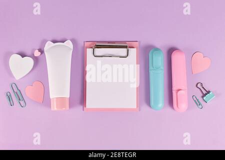 Clipboard with empty paper for text next to stationery items like marker pens, clips and hearts on pastel violet background Stock Photo