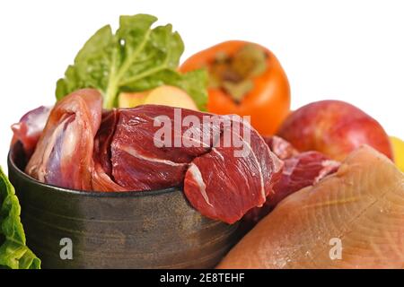 Close up of dog bowl with mixture of biologically appropriate raw food containing meat chunks, fish, fruits and vegetables isolated on white backgroun Stock Photo