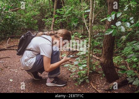 Teenage girl taking photographs with her mobile phone in forest. Stock Photo
