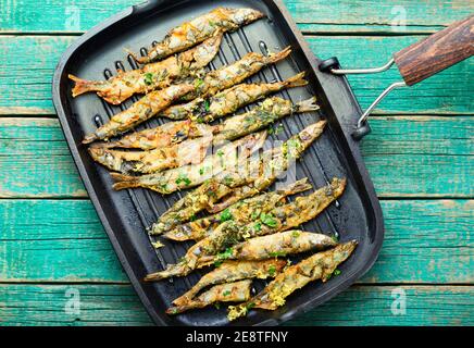 Fried capelin garnished with parsley and lemon zest in a pan Stock Photo