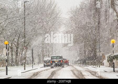 A black can drives over a zebra crossing in heavy snow in London Stock Photo