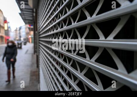 01 February 2021, Saxony-Anhalt, Halle (Saale): A passerby walks past a closed shop in the city center. Restrictions on public life remain in place across the country to contain the Corona pandemic. Photo: Hendrik Schmidt/dpa-Zentralbild/dpa Stock Photo
