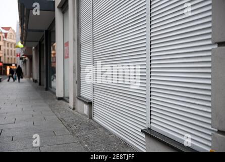 01 February 2021, Saxony-Anhalt, Halle (Saale): Shutters close a shop in a shopping street in Halle/Saale. Restrictions on public life remain in place across the country to contain the Corona pandemic. Photo: Hendrik Schmidt/dpa-Zentralbild/dpa Stock Photo
