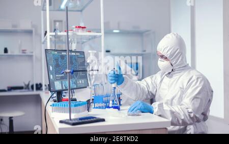 Researcher scientist working with micropipette in big scientific lab. Chemist in modern laboratory doing research using dispenser during global epidemic with covid-19. Stock Photo